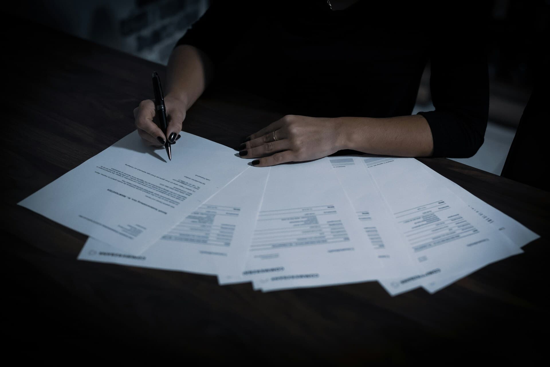 Hands signing a set of printed documents at a desk