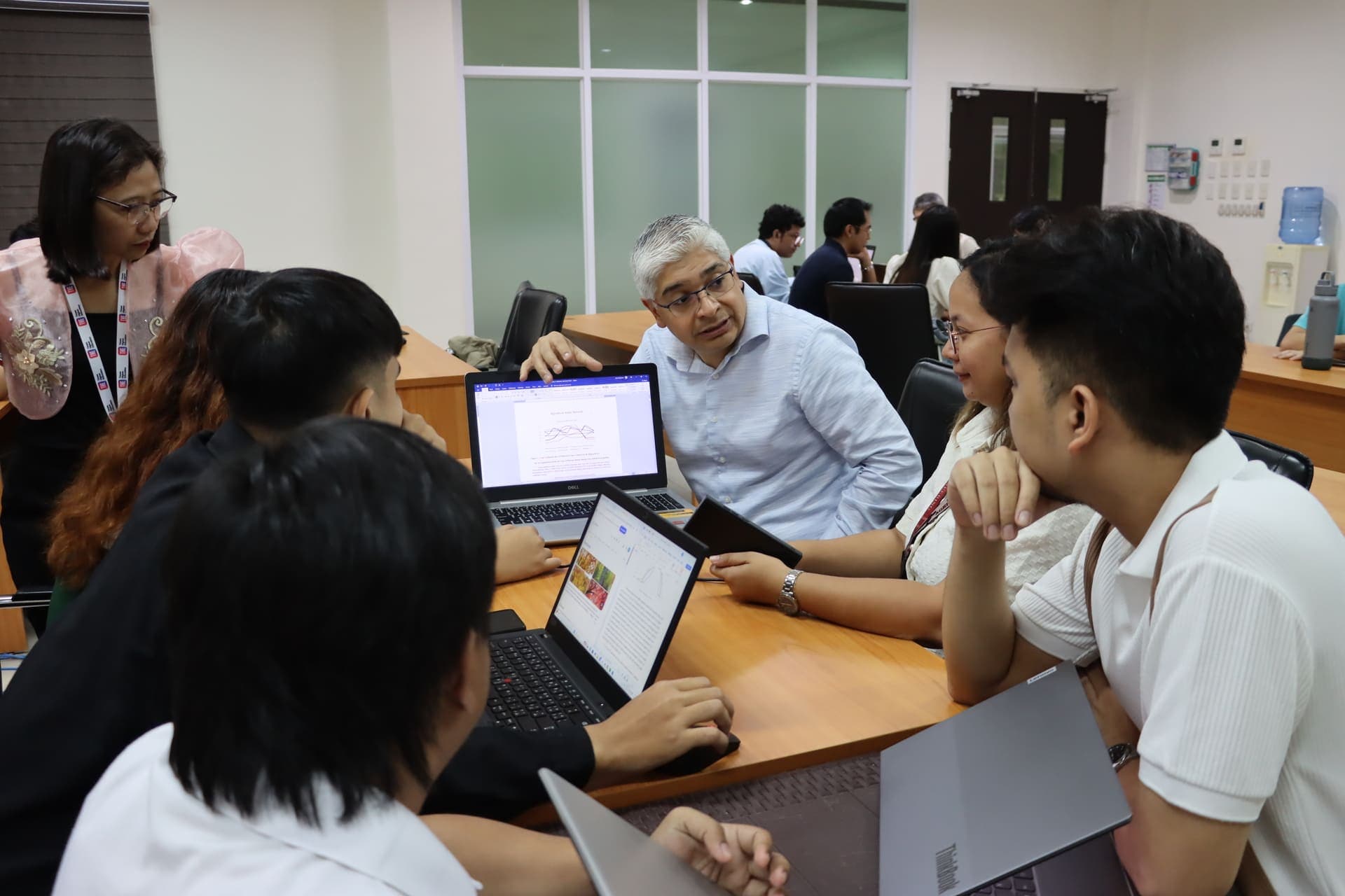 Volunteer Dr. Samuel Sandoval Solis working with faculty and students on laptops during training at Central Luzon State University, Philippines
